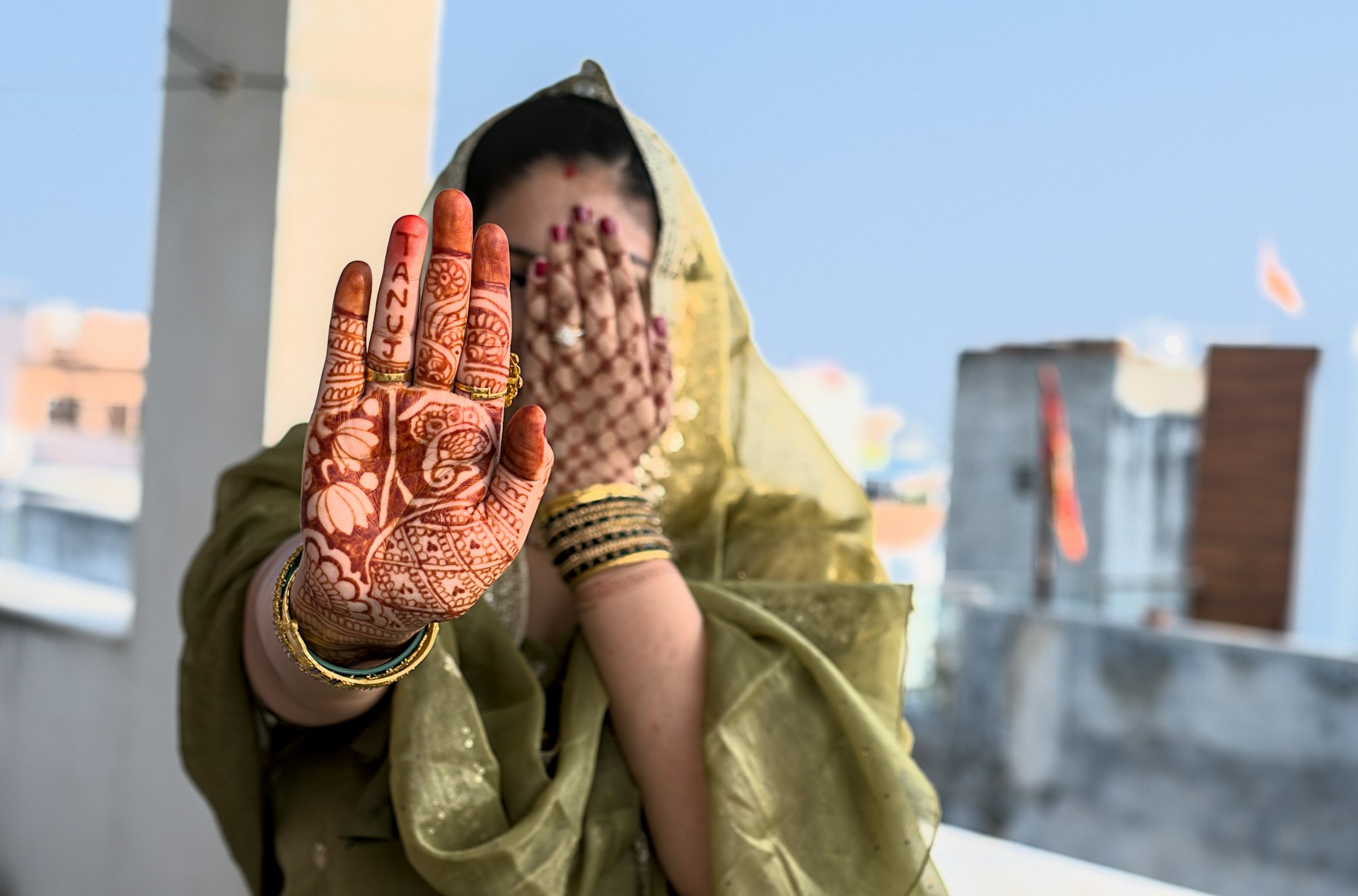 A woman in a green sari holding her hands up to her face